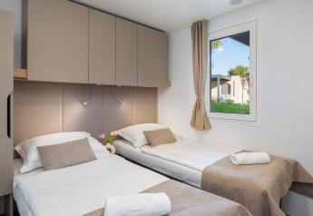 Camera chalet moderna con due letti singoli, finestra e armadi presso Aminess Style Camping Avalona Resort in Croazia.