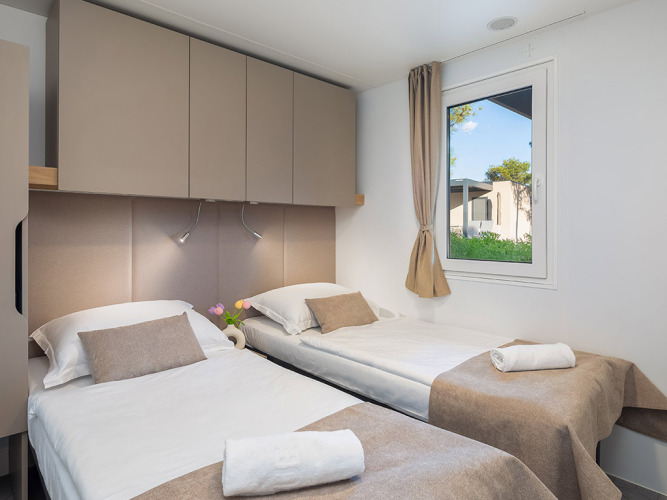 Camera chalet moderna con due letti singoli, finestra e armadi presso Aminess Style Camping Avalona Resort in Croazia.