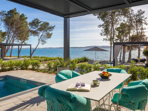 Buitenterras met zwembad, moderne stoelen en zeezicht bij een luxe vakantiehuis in Kroatië.