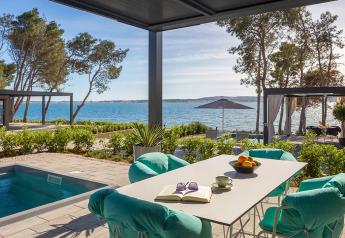Terrazza con piscina, poltrone moderne e vista mare in una casa vacanze di lusso in Croazia.