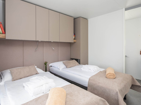 Chalet moderno con dos camas individuales, ropa de cama beige y armarios en Aminess Style Camping Avalona Resort.