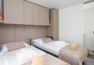 Moderne chaletkamer met twee eenpersoonsbedden, beige linnengoed en kasten bij Aminess Style Camping Avalona Resort.
