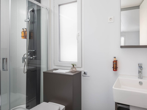 Baño moderno con ducha, ventana, lavabo y espejo en lujoso chalet de Aminess Style Camping Avalona Resort en Croacia.