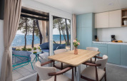 Chalet moderno con comedor, cocina y vista al mar en Aminess Style Camping Avalona Resort, Croacia.
