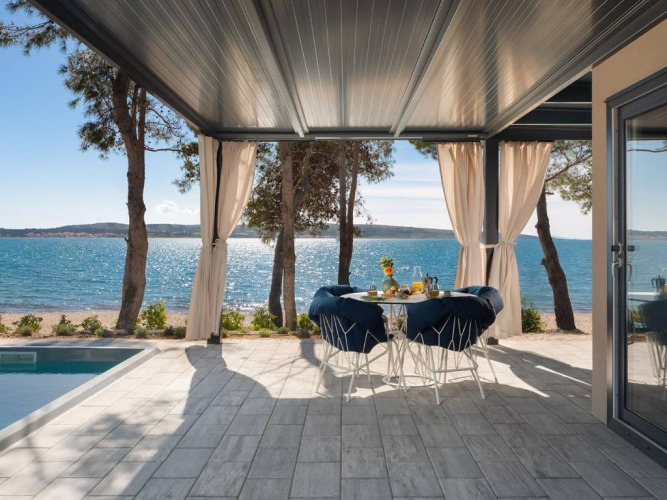 Terrazza con vista mare, tavolo da pranzo e piscina sulla spiaggia ad Amber Sea Luxury Holiday Home in Croazia.