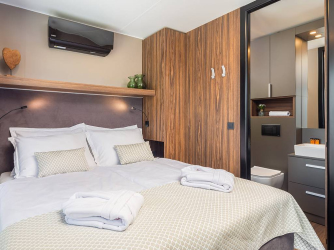 Soveværelse med dobbeltseng, badeværelse og moderne interiør i Luxury Glamping Villa Pool på Aminess Style Camping Avalona Resort, Kroatien.