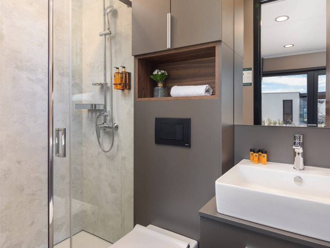 Moderne badeværelse med bruseniche, håndvask og spejl i en chalet på Aminess Style Camping Avalona Resort.