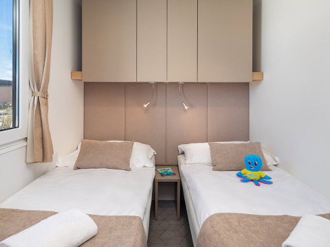 Camera da letto moderna con due letti singoli e arredi beige all'Aminess Style Camping Avalona Resort.
