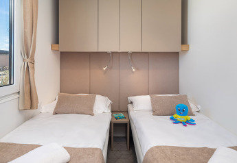 Camera da letto moderna con due letti singoli e arredi beige all'Aminess Style Camping Avalona Resort.
