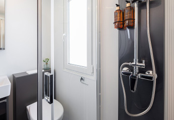 Bagno moderno con doccia, WC e finestra al Family Premium Holiday Home, Aminess Style Camping Avalona Resort, Croazia.