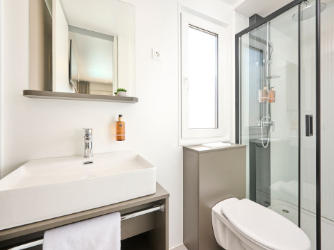 Baño moderno con lavabo grande, espejo, ducha, ventana y sanitario en Amber Sea Luxury Holiday Home.