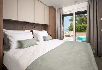 Moderne slaapkamer in Amber Sea Luxury Holiday Home met zicht op privézwembad in Kroatië.