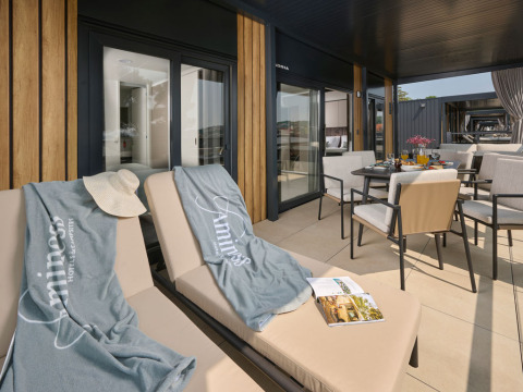 Terrazza soleggiata con lettini e tavolo da pranzo ad Amber Luxury Holiday Home, Aminess Style Camping Atea Resort, Croazia.