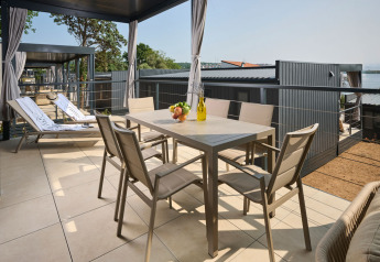 Udendørs terrasse med spisebord, stole og liggestole på Premium Holiday Home ved Aminess Style Camping Atea Resort i Kroatien.