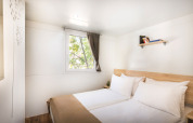 Bright bedroom with double bed, shelf, and window at Comfort Holiday home, Aminess Style Camping Atea Resort, Croatia.