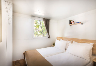 Dormitorio luminoso con cama doble, ventana y estante en Comfort Holiday home, Aminess Style Camping Atea Resort, Croacia.