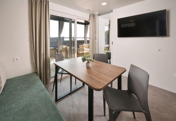 Moderne spiseplads med træbord, sorte stole og udsigt til terrasse i Premium Holiday Home, Camping Atea, Kroatien.