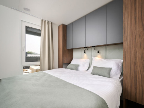 Camera moderna con letto matrimoniale, dettagli in legno e ampia finestra al Premium Holiday Home in Croazia.