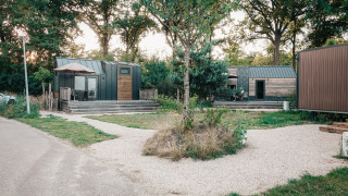 Petites maisons modernes en bois entourées d’arbres, photo prise à Tiny House en fin de journée.