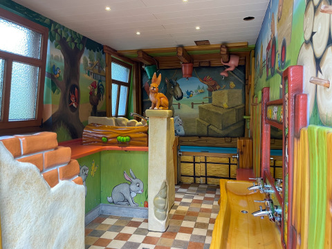 Bagno per bambini con disegni di animali e murales colorati presso Camping Fuussekaul, Wiltz, Lussemburgo.