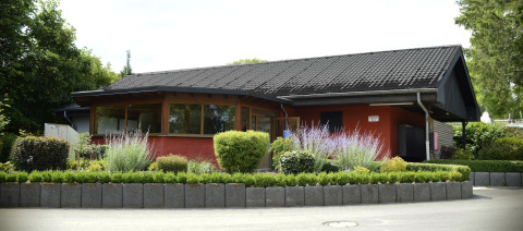 A cozy holiday house with lush planting at Camping Fuussekaul holiday park in Wiltz, Luxembourg.