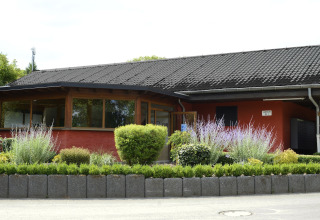 A cozy holiday house with lush planting at Camping Fuussekaul holiday park in Wiltz, Luxembourg.