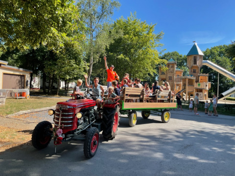 Kinderen en volwassenen genieten van een tractorrit aan de speeltuin bij Camping Fuussekaul in Wiltz.