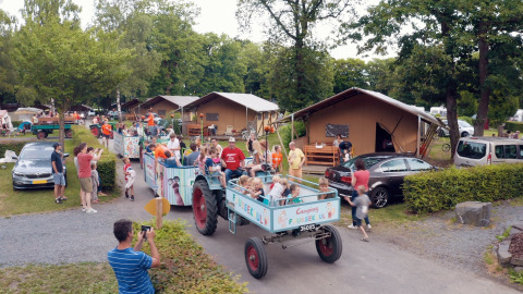 Bambini e famiglie si godono un giro festoso in trattore al Camping Fuussekaul, un villaggio vacanze a Wiltz, Lussemburgo.