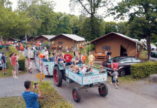 Children and families enjoying a festive tractor ride through Camping Fuussekaul holiday park in Wiltz, Luxembourg.