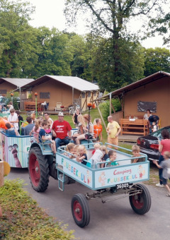 Kinderen en gezinnen genieten van een feestelijke tractorrit op Camping Fuussekaul in Wiltz, Luxemburg.