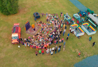 Vista aerea di un evento all'aperto con persone, veicoli colorati e stand a Camping Fuussekaul, Wiltz.
