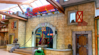 Overdekte speeltuin op Camping Fuussekaul in Wiltz, Luxemburg, met ridderkasteel en buizenglijbaan.