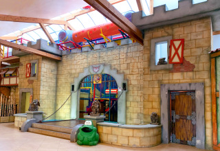 Indoor playground at Camping Fuussekaul in Wiltz, Luxembourg, featuring a castle design and tube slide.