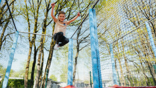 Een kind springt op een trampoline in openlucht op Camping Fuussekaul, Wiltz, Luxemburg.