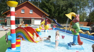 Kinderen spelen in een ondiep zwembad met glijbaan bij Camping Fuussekaul in Wiltz, Luxemburg.