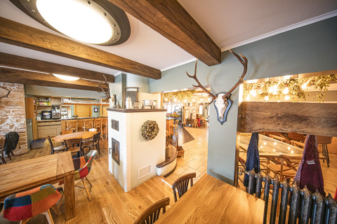 Interno accogliente di ristorante con travi in legno e decorazioni con corna al Camping Fuussekaul, Wiltz, Lussemburgo.