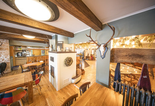 Interno accogliente di ristorante con travi in legno e decorazioni con corna al Camping Fuussekaul, Wiltz, Lussemburgo.