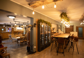Cozy restaurant interior at Camping Fuussekaul in Wiltz, Luxembourg, featuring warm lighting.