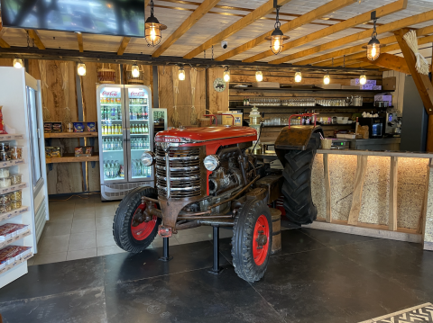Indoor café scene at Camping Fuussekaul, with a vintage red tractor decor and rustic wooden details.