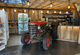 Indendørs café med en retro rød traktor som dekoration, køleskabe og rustikke trædetaljer i Wiltz.