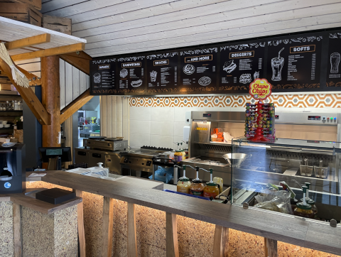 Snack bar at Camping Fuussekaul in Wiltz, Luxembourg with menu boards and a Chupa Chups lollipop display.