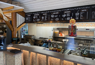 Snack bar at Camping Fuussekaul in Wiltz, Luxembourg with menu boards and a Chupa Chups lollipop display.