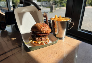 Een hamburger en frietjes in een metalen emmer op een tafel bij Camping Fuussekaul in Wiltz, Luxemburg.