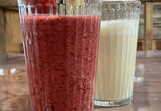 To glas med smoothies og mælk på et bord på Camping Fuussekaul i Wiltz, Luxembourg, med friske jordbær.