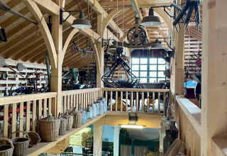 Intérieur rustique d'une grange au Camping Fuussekaul, Wiltz, avec poutres en bois et paniers anciens.