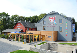 Camping Fuussekaul in Wiltz, Luxembourg, showing Brasserie Restaurant, outdoor pergola, and park signage.