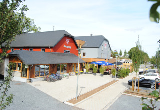 Photo of Camping Fuussekaul holiday park in Wiltz, Luxembourg, showing bikes, terrace, and parking area.