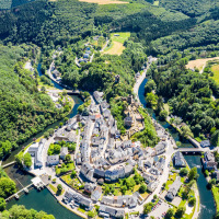 Luftaufnahme eines Ferienparks mit Glamping-Unterkünften in einer idyllischen Flussschleife im Grünen.