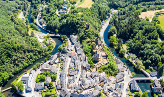Luchtfoto van een vakantiepark met glampingplekken, prachtig gelegen in een groene, bochtige riviervallei.