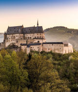 Beeindruckende Burg auf bewaldetem Hügel bei Sonnenuntergang, nahe einem Glamping-Ferienpark gelegen.